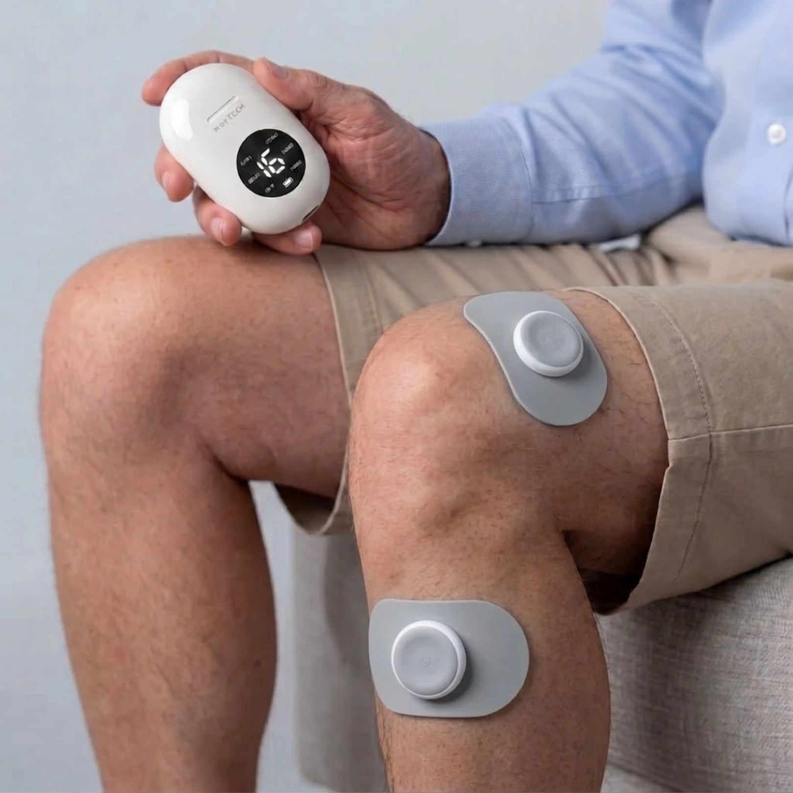 Movtech Electrowave TENS elektródák a térden, ülő helyzetben, kézben a vezérlővel