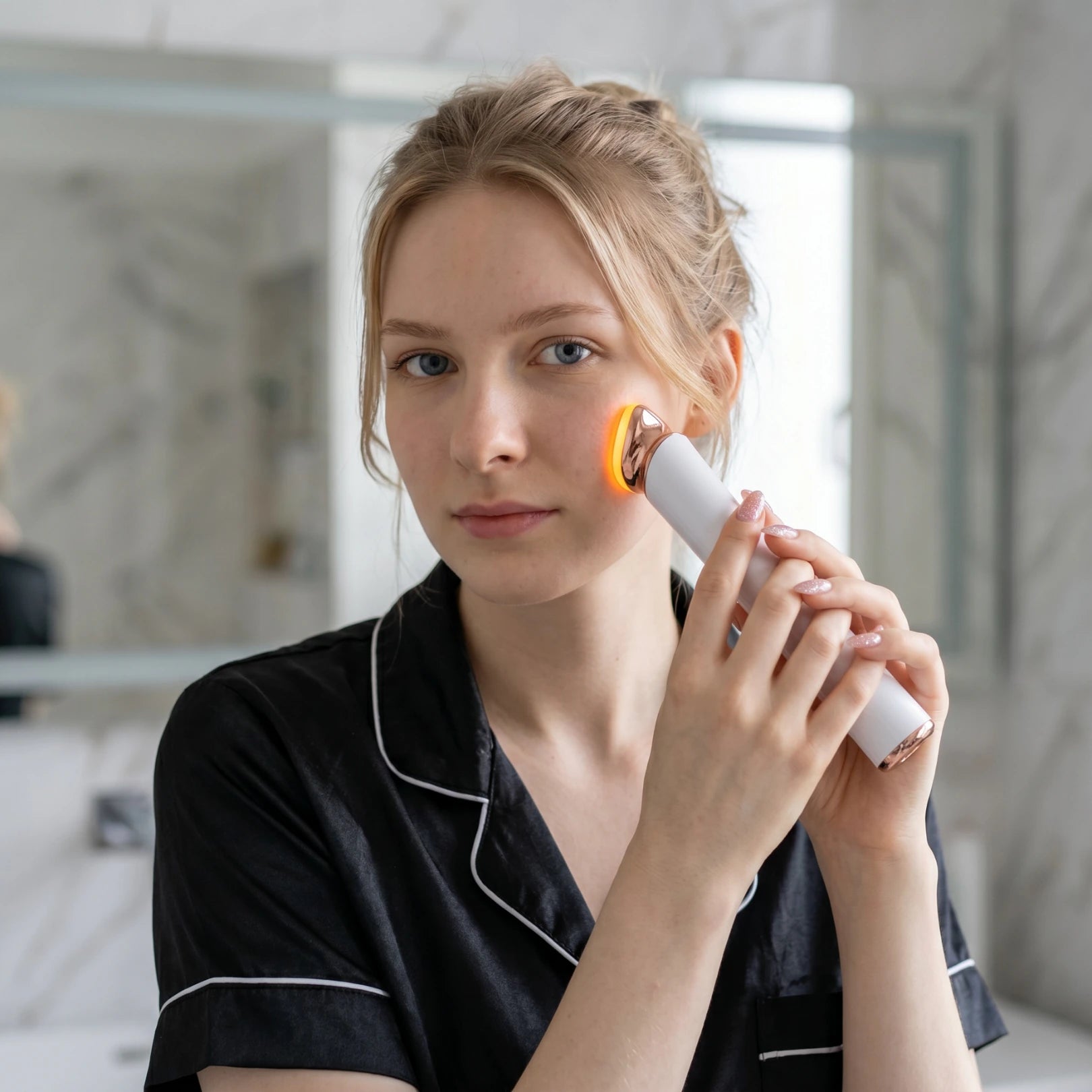 Movtech SkinGlow vörösfényes arcápoló készülék használata a fürdőszobában, feltűzött hajú nő arcán