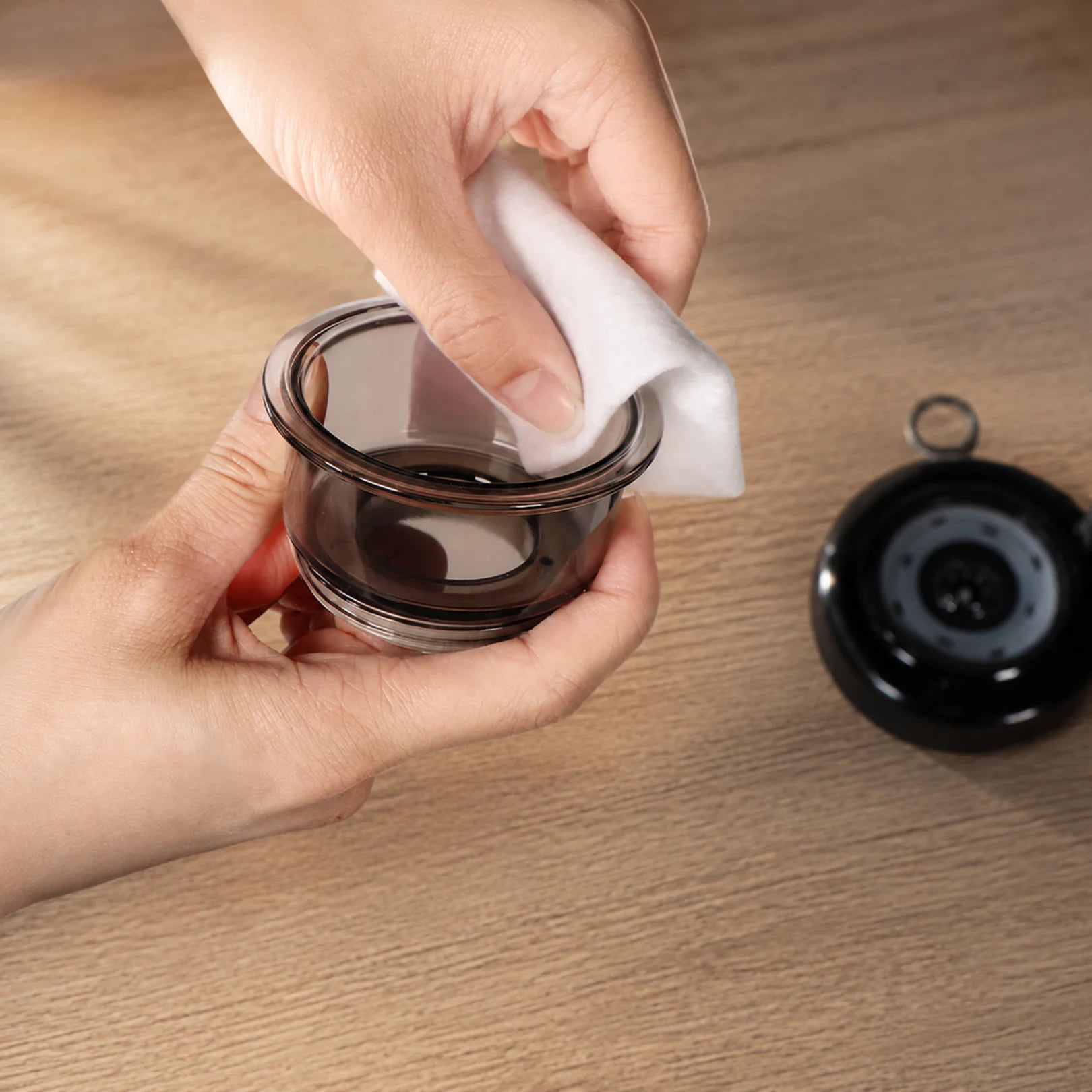 A Movtech Smart Cupper okos köpölyöző poharának tisztítása kendővel, mellette a készülék
